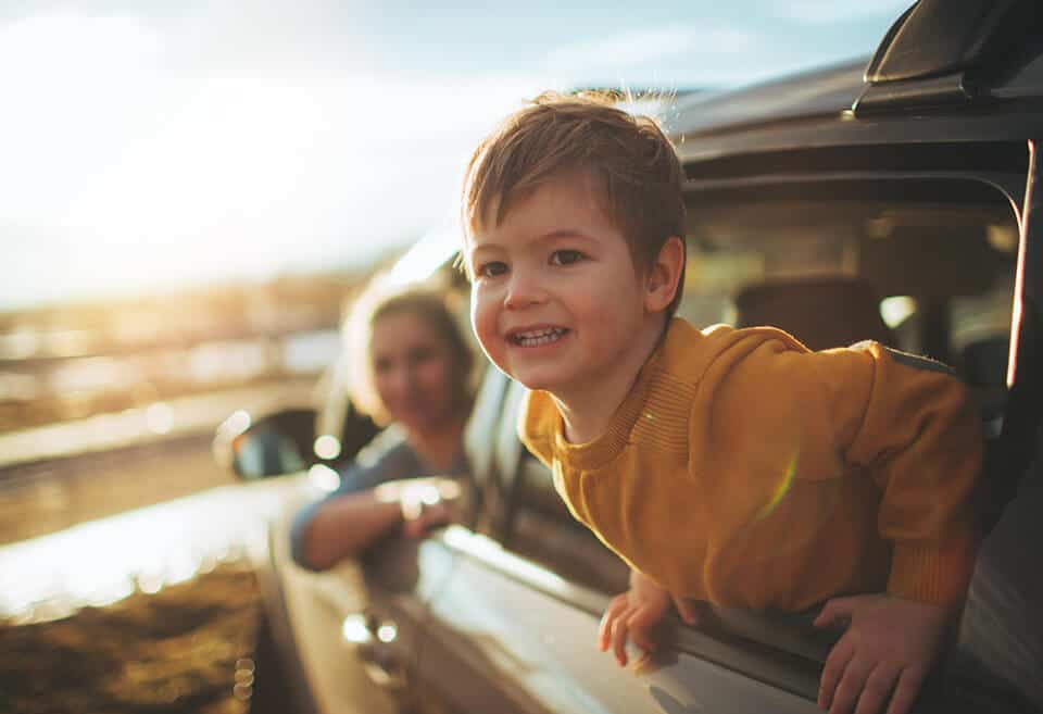 Child smiling and leaning out of car window
