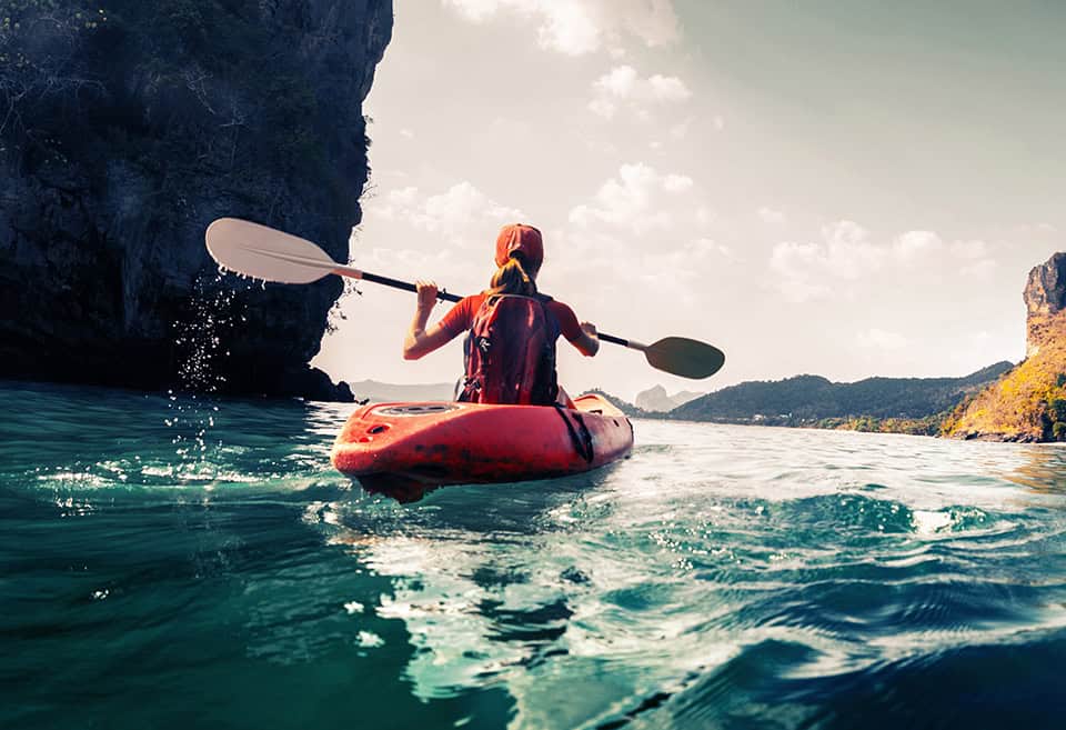 Woman kayaking away from camera towards open waters