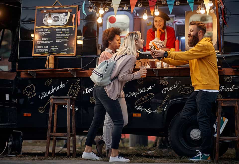Group of friends having fun and chatting while ordering food at a food truck