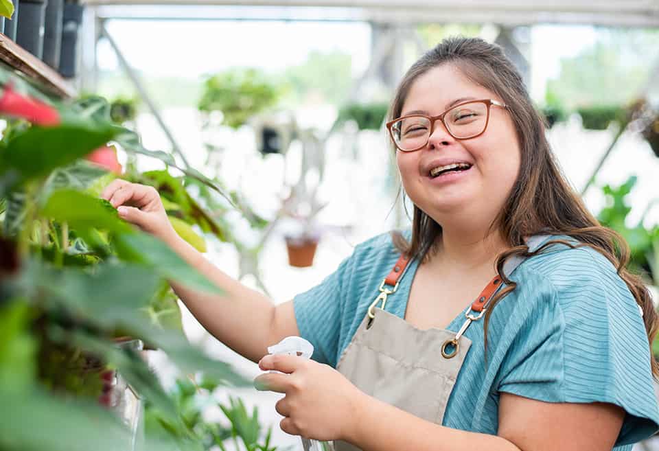 Person watering plants and smiling