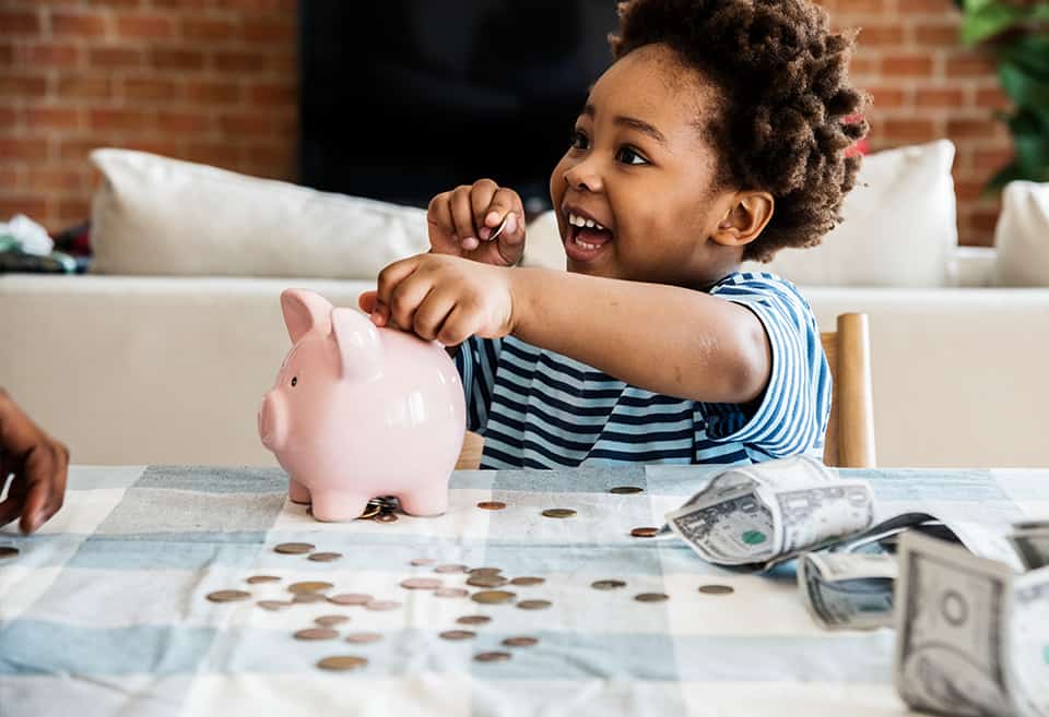 Child putting coins in a piggy bank