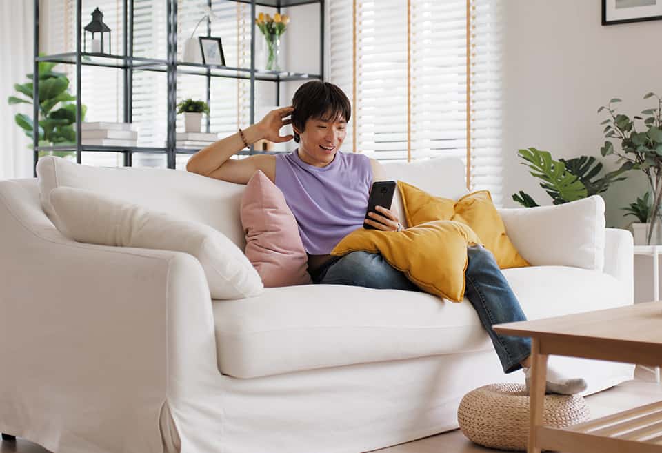 Person sitting on couch looking at their mobile banking app