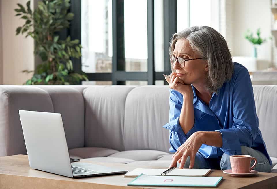 Person looking at their laptop screen along with two open notebooks spread on the table