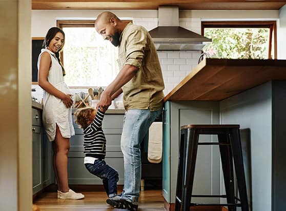 A young family smiling and laughing together in the kitchen of their home