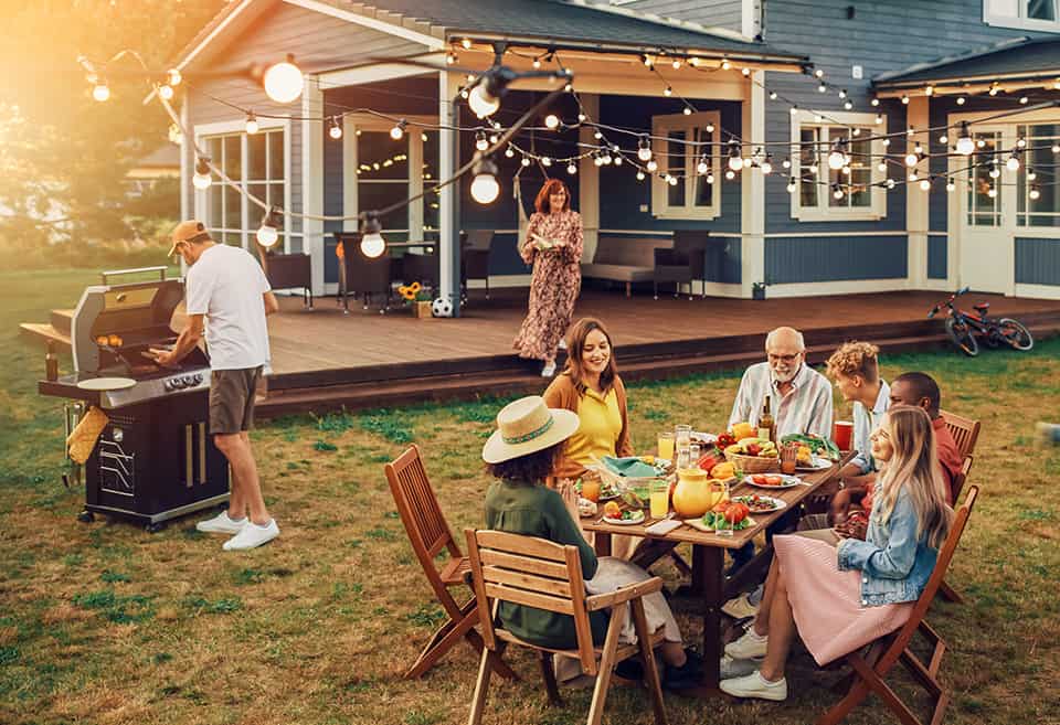 Big group of people eating and cooking in a backyard celebration