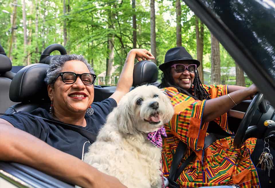 Couple with their dog driving in a convertible