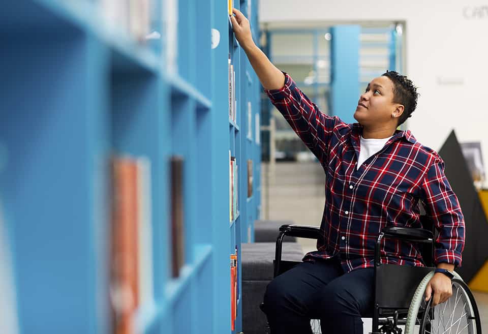 Student in wheelchair looking at library books