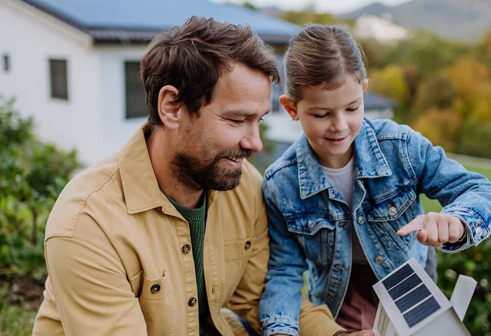 Father explaining solar loans to his daughter while holding model home