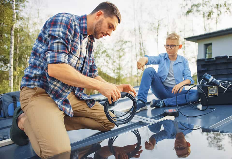 A parent and child working together to install a solar panel on their home