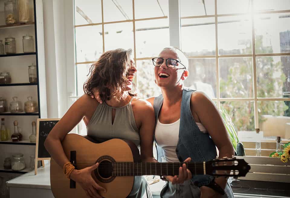Two friends laughing and singing as one of them plays guitar