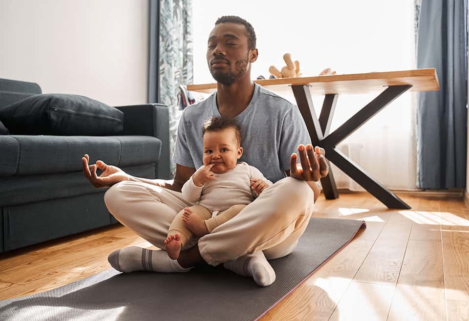 Parent and child sit on yoga mat meditating