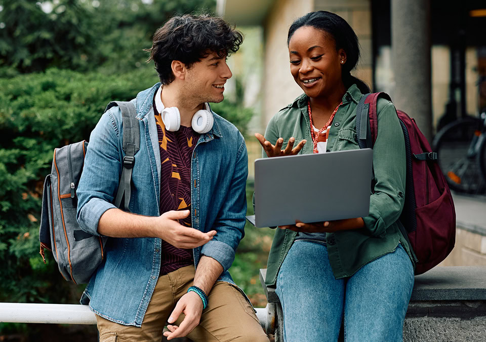 Two students standing together looking at a laptop