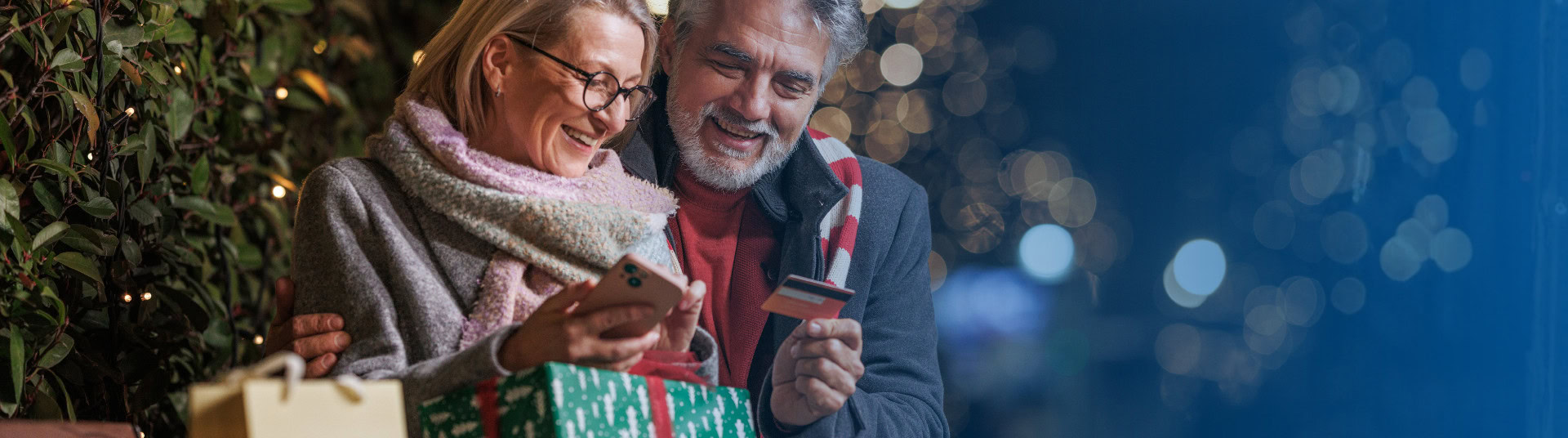 Elderly couple smiling, shopping online and paying with a BluPeak debit card.