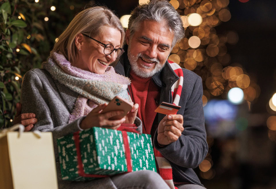 Elderly couple smiling, shopping online and paying with a BluPeak debit card.