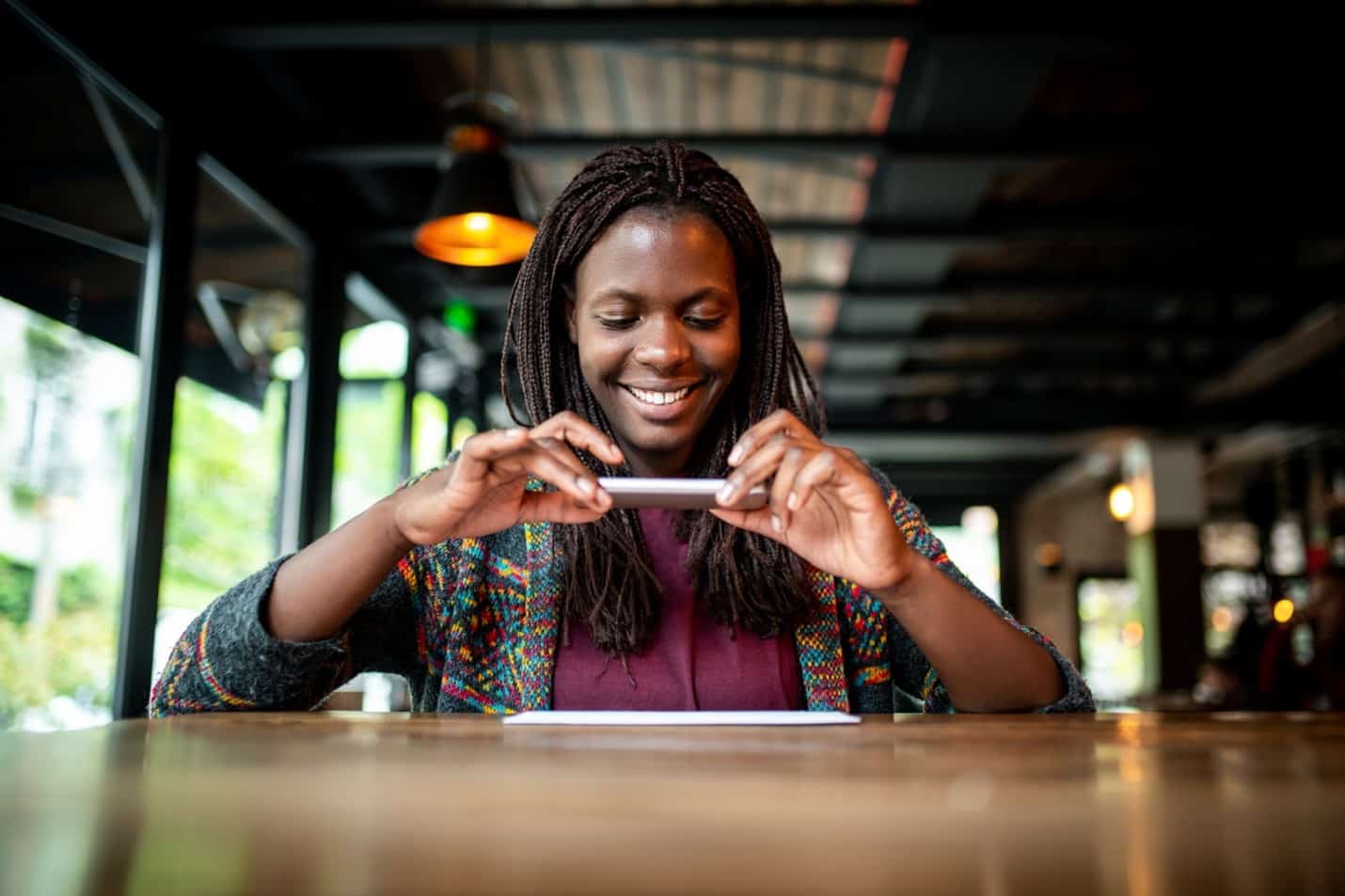 Young woman takes a picture of her check to use mobile check deposit through her BluPeak mobile banking so she can reach her financial goals.