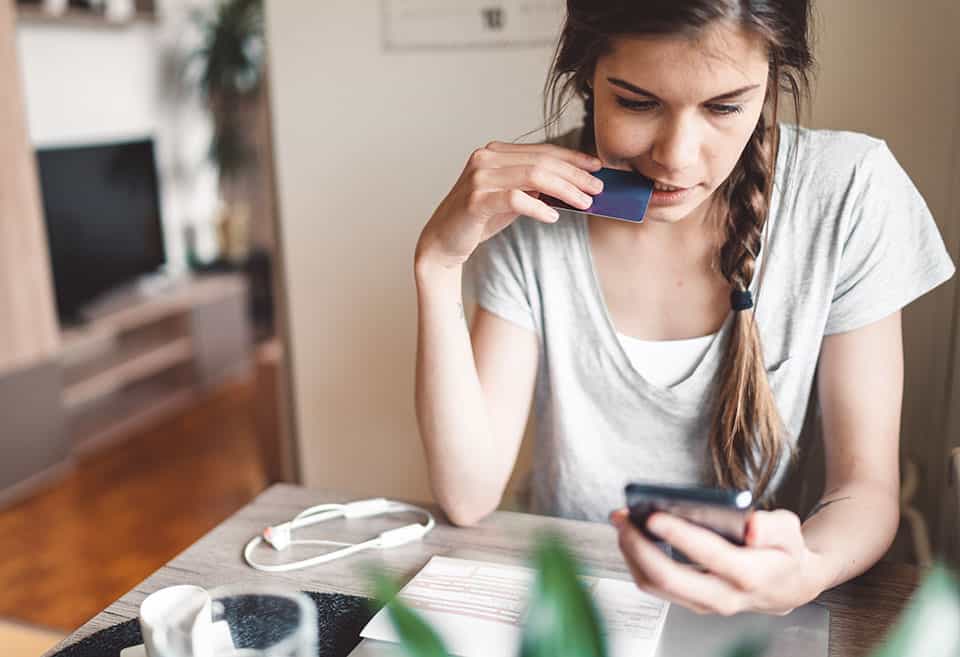 Woman thinking and looking at her phone screen