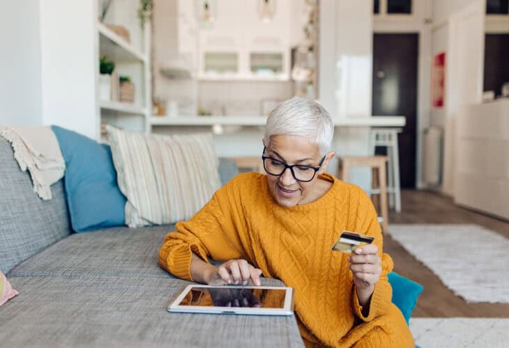 Person online shopping on a tablet and paying with a credit card.