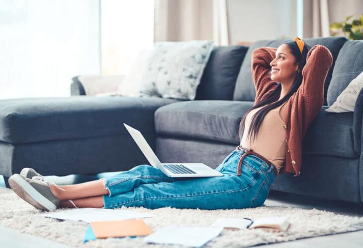 Person sitting on floor working on laptop.