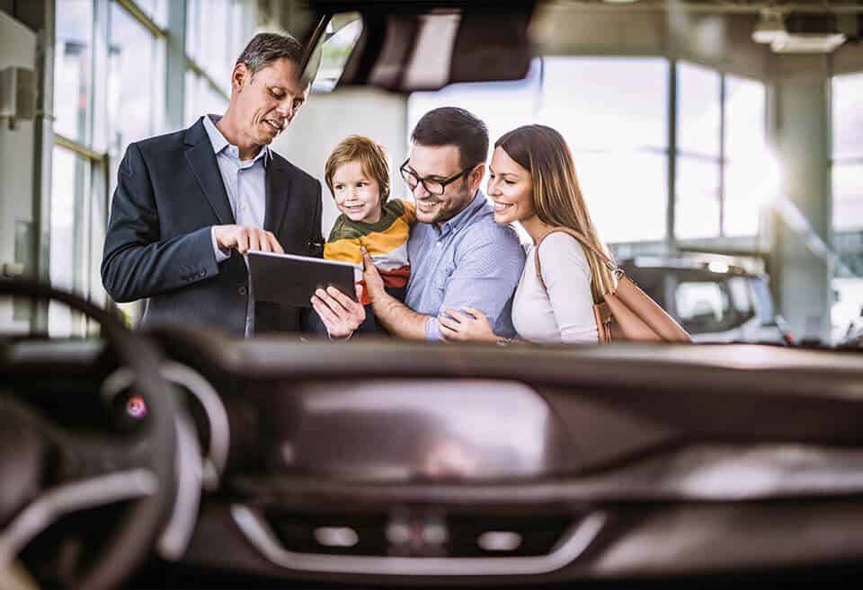 family of three purchasing a new car from dealership