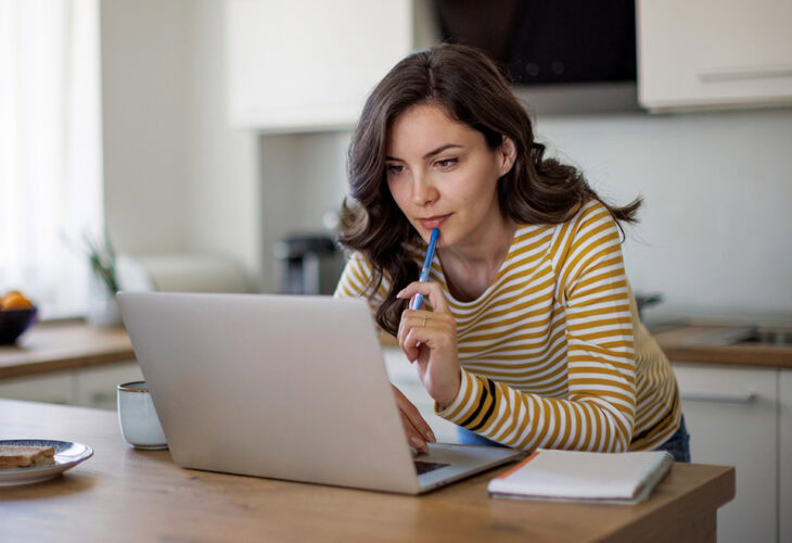 Woman on laptop with notepad