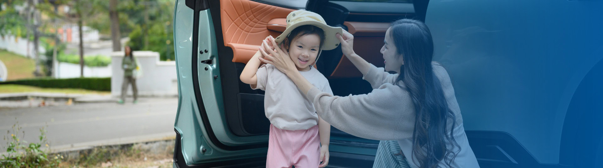 Mother putting a hat on her toddler after they've stepped out from her vehicle