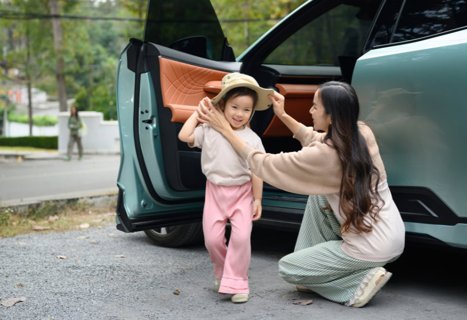 Mother putting hat on her toddler after stepping out from her vehicle