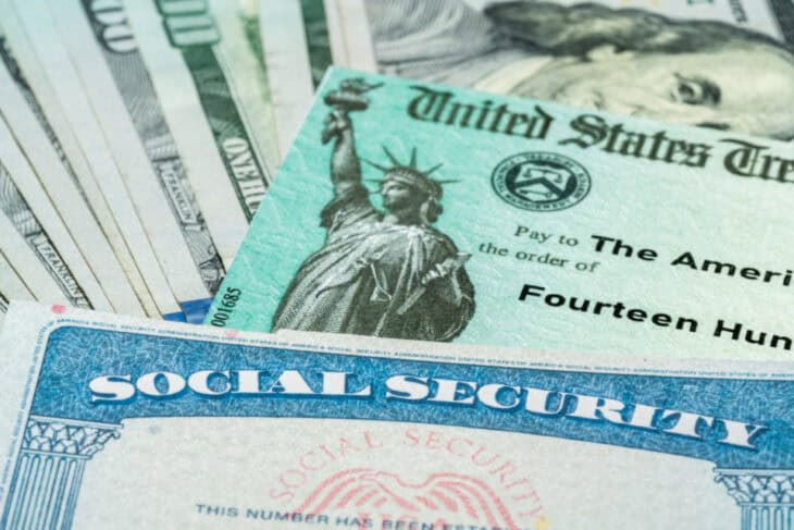 A social security card alongside a social security check and some cash.